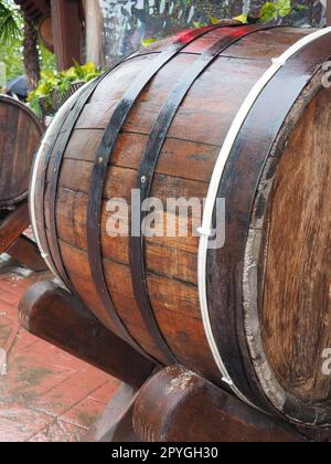 A traditional old wooden barrel with curved walls and metal hoops. Dishes for the ripening of alcoholic beverages - mead, beer, wine, whiskey. A rollable cylindrical vessel for liquid substances. Stock Photo