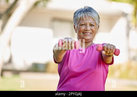 No getting old here. Portrait of a mature woman lifting dumbbells outside. Stock Photo