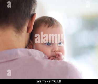 Daddys little angel. a baby girl looking over her fathers shoulder. Stock Photo