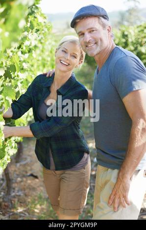 We care about our fresh produce. Happy mature couple checking the vines in their vineyard together. Stock Photo