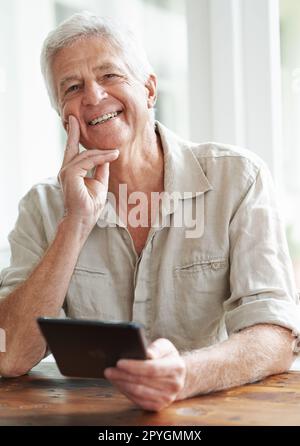 I love all these new technological toys. A happy senior man looking away thoughtfully as he holds a digital tablet. Stock Photo