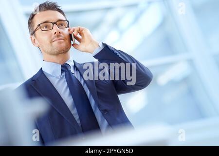 Taking a corporate call. Handsome mature businessman on his mobile while looking away. Stock Photo