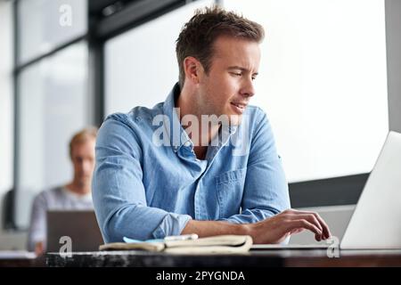Wifi works for him. a man working on a laptop in an office. Stock Photo