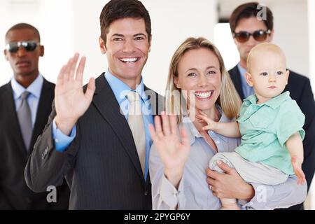 Waving to the crowds. a politician and his family waving at a public event with bodyguards protecting them. Stock Photo