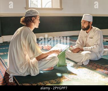 Quran, muslim and mosque with an imam teaching a student about religion, tradition or culture during eid. Islam, book or worship with a religious teacher and islamic male praying together for ramadan Stock Photo