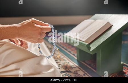 Quran, beads or hands praying in Islamic or Muslim religion to Allah for spiritual peace or freedom in mosque in Qatar. Muslim pray, reading or person kneeling on carpet in holy temple to praise God Stock Photo