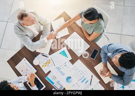 Business people, handshake and meeting with finance report documents for a b2b proposal with an accounting team. Men and women at table for planning with applause and shaking hands for profit growth Stock Photo