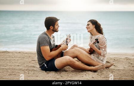 Our passion for music made us passionate about each other. a young couple playing the ukulele on the beach. Stock Photo