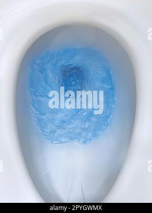 Top view of toilet bowl, blue detergent flushing in it Stock Photo