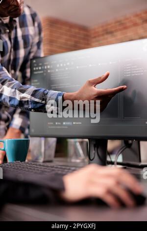 Enginners discussing about coding script compiling discovers errors, standing in front of multiple screens in startup office. Diverse programmers working on server interface development. Stock Photo