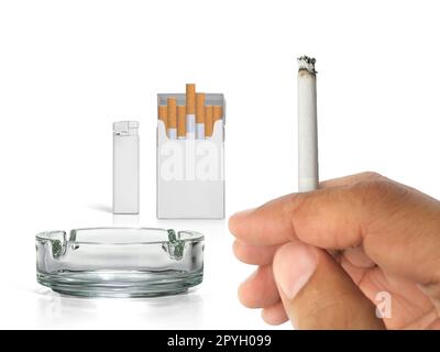 A cigarette in a hand, Cigarette pack, ashtray, and lighters isolated on white background Stock Photo