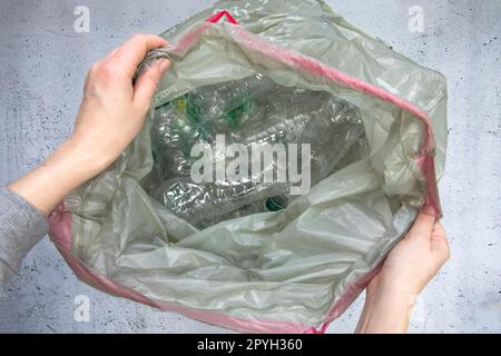 Hand getting plastic bottles to dispose in garbage bag ready to recycle, waste management and plastic recycle. Sorting waste plastic bottles top view Stock Photo