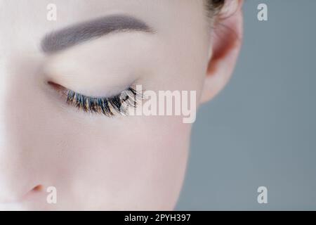 Close-up of closed eye with magnificent long eyelashes, flawless skin, eyebrow of unrecognizable young woman. Macro. Stock Photo