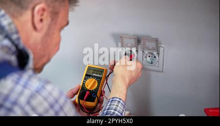 Male Electrician Checking Voltage Of Socket With Multimeter Stock Photo