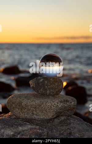 The glass ball lies on the top stone reflecting the beach and the sea ...