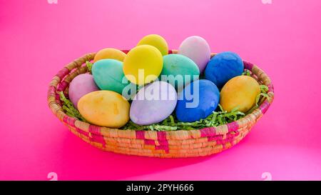 Colorful bright  Easter eggs inside basket on pink background Stock Photo