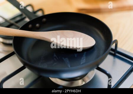 Spatula in skillet teflon coating pan on gas stove against spoon hanging in small kitchen Stock Photo