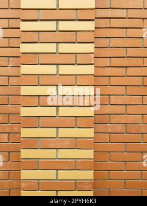 The modern texture of an orange brick wall with a yellow brick ornament is the background material of industrial construction Stock Photo
