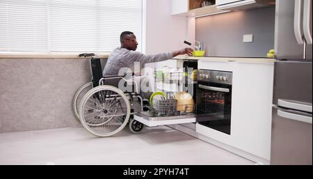 Young Man Sitting On Wheelchair Arranging Plates Stock Photo