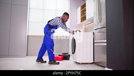 Young Man In Overall Repairing Washing Stock Photo