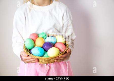 A little girl, five years old, holding a wooden basket with many colored Easter eggs in her hands. Stock Photo