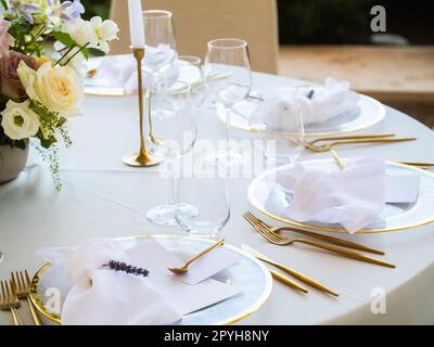 Beautiful outdoor wedding decoration in city. Candles and dried flowers and accessories with bouquets and glasses on table with linen tablecloth on newlywed table on green lawn Stock Photo
