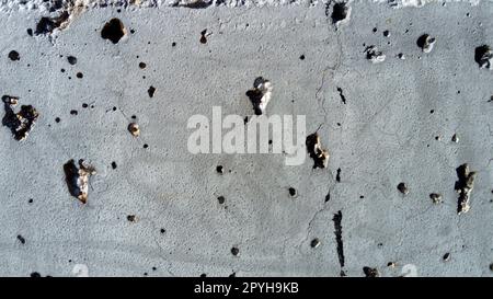 Concrete wall with concentric damage of large radius. Potholes, tubercles and defects. Grey colour. Planet surface concept. Concrete wall with a worn surface, potholes, bulges and small spots. Stock Photo