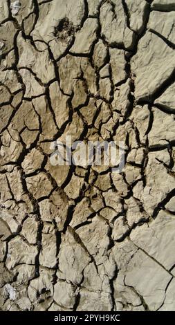 cracked clay soil due to drought and waste of river water. Red earth Stock Photo