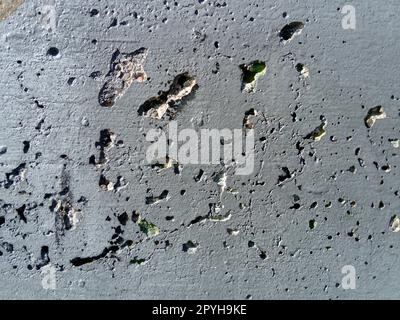 Concrete wall with concentric damage of large radius. Potholes, tubercles and defects. Grey colour. Planet surface concept. Concrete wall with a worn surface, potholes, bulges and small spots. Stock Photo