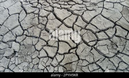 cracked clay soil due to drought and waste of river water. Stock Photo