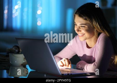 Happy woman watching media on laptop at home Stock Photo