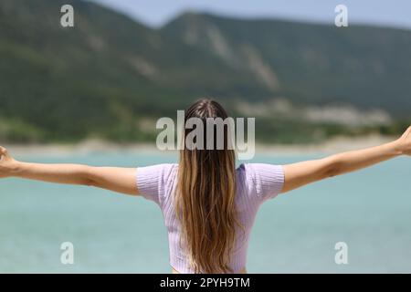 Back view of a woman outstretching arms in nature Stock Photo
