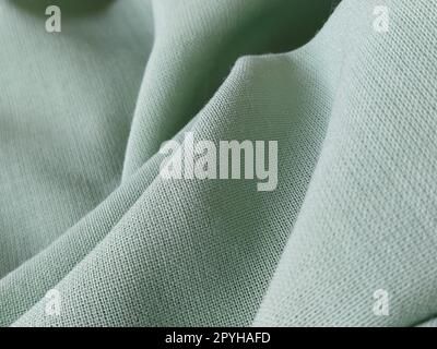 Close up of a woolen fabric of green color. Abstract canvas background, empty template. Thin natural fabric, wool or linen Stock Photo