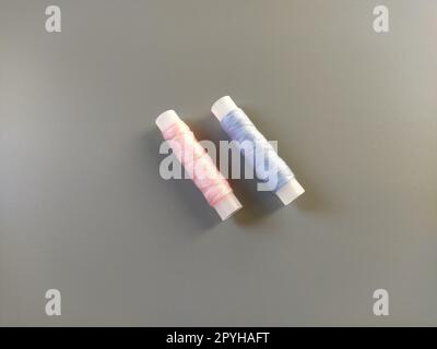 Spools of pink and blue thread on a gray background. Textile industry Stock Photo