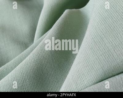 Close up of a woolen fabric of green color. Abstract canvas background, empty template. Thin natural fabric, wool or linen Stock Photo