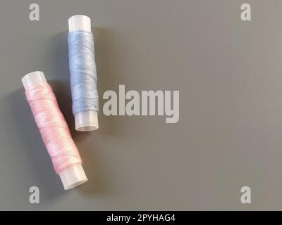 Spools of pink and blue thread on a gray background. Textile industry Stock Photo