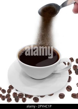 Hand pours instant coffee from a spoon in a coffee Stock Photo