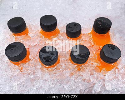 Homemade Fresh Orange juice bottles on the ice box. Mix of plastic bottles on the ice bucket for sale in Thailand food market Stock Photo