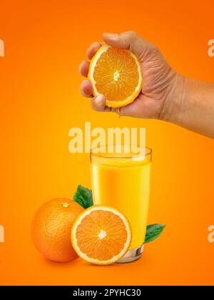 Hand squeezing orange into glass and orange fruit on the isolated on orange background Stock Photo