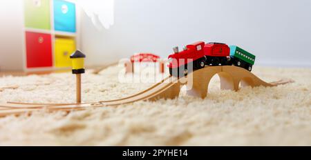 Closeup view of the toy train on the wooden bridge on the floor indoors. Stock Photo