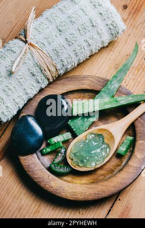 Top view of aloe vera spa and wellness cosmetic product for skin and beauty care. Herbal natural aromatherapy and zen massage stones on vintage wooden table. Stock Photo