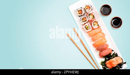 Sushi rolls set with salmon and tuna fish on light blue background from above. Stock Photo