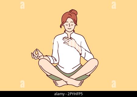 Woman meditates with hand on heart and wishes to heal herself through yoga and Buddhist spiritual practices. Girl sitting in lotus position takes care Stock Photo