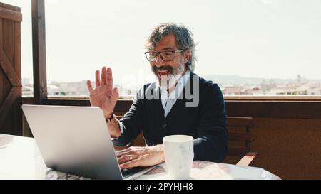 Happy middle aged man communicates remotely using laptop. Working from home office Stock Photo