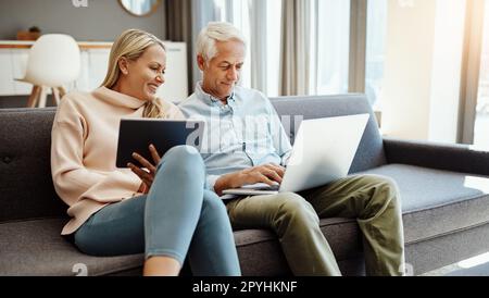 This is what happens when you save for retirement. a mature couple using a digital tablet and laptop on the sofa at home. Stock Photo