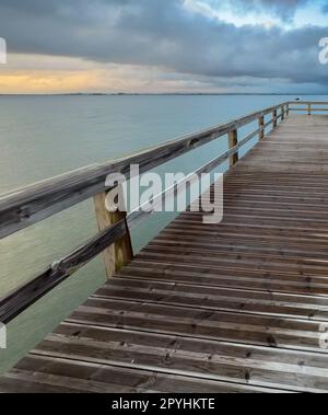 Empty wooden pier to the Ria de Aveiro in Portugal, with dramatic sky and calm water. Torreira, Murtosa - Portugal. Stock Photo