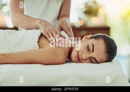 Making muscle tension a thing of the past. an attractive young woman getting massaged at a beauty spa. Stock Photo