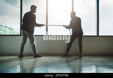 No one pushes you to achieve more than your competitor. two young businessmen pulling on a rope in a game of tug of war. Stock Photo
