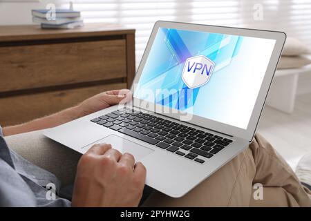 Man using laptop with switched on VPN indoors, closeup Stock Photo
