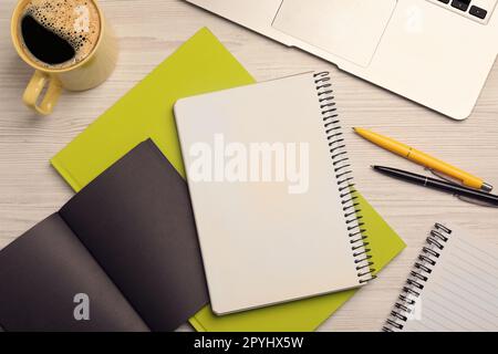 Flat lay composition with different notebooks, coffee and pens on wooden table Stock Photo